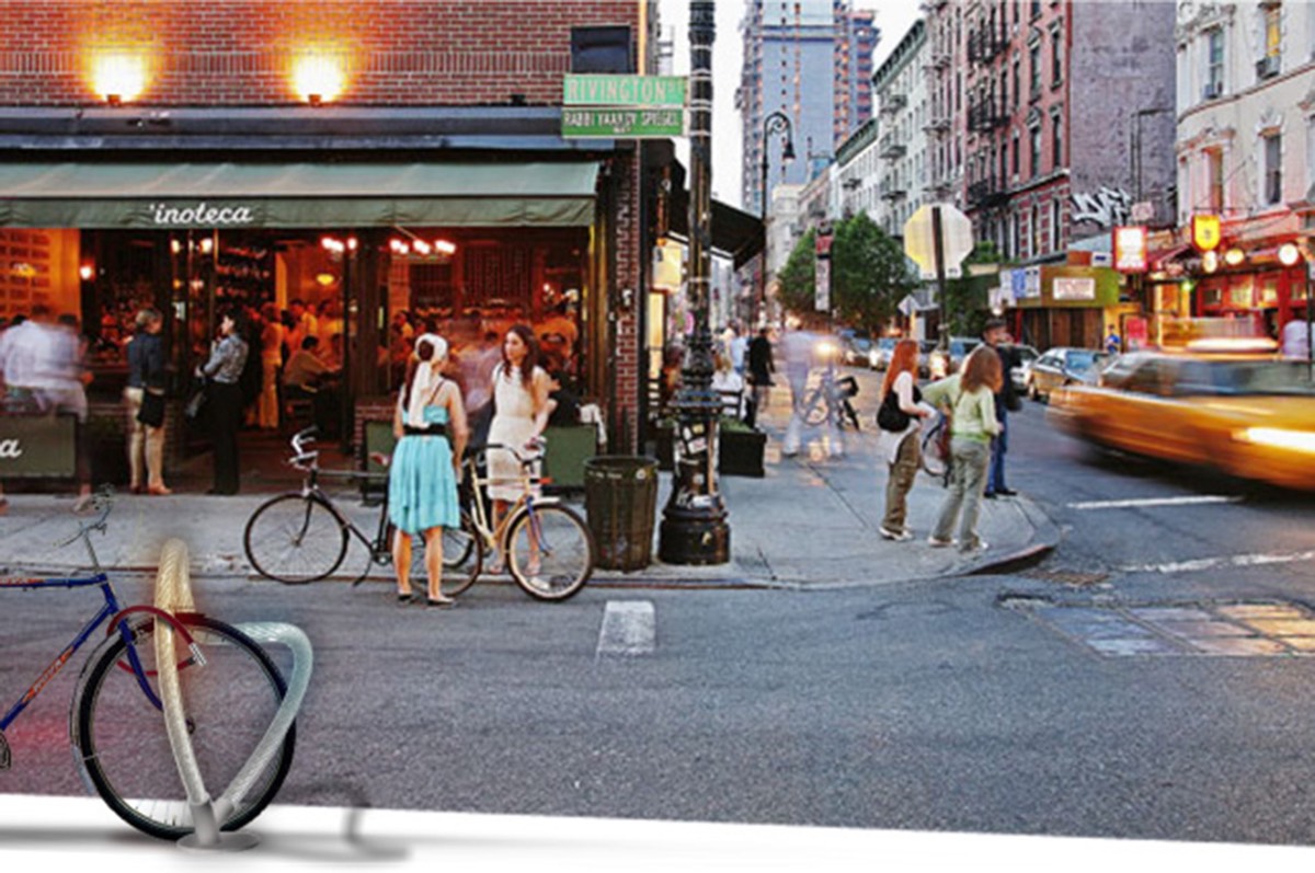 A pale loop-shaped rack with a blue bike composited into a street photograph of Rivington Street at dusk, people and a taxi passing