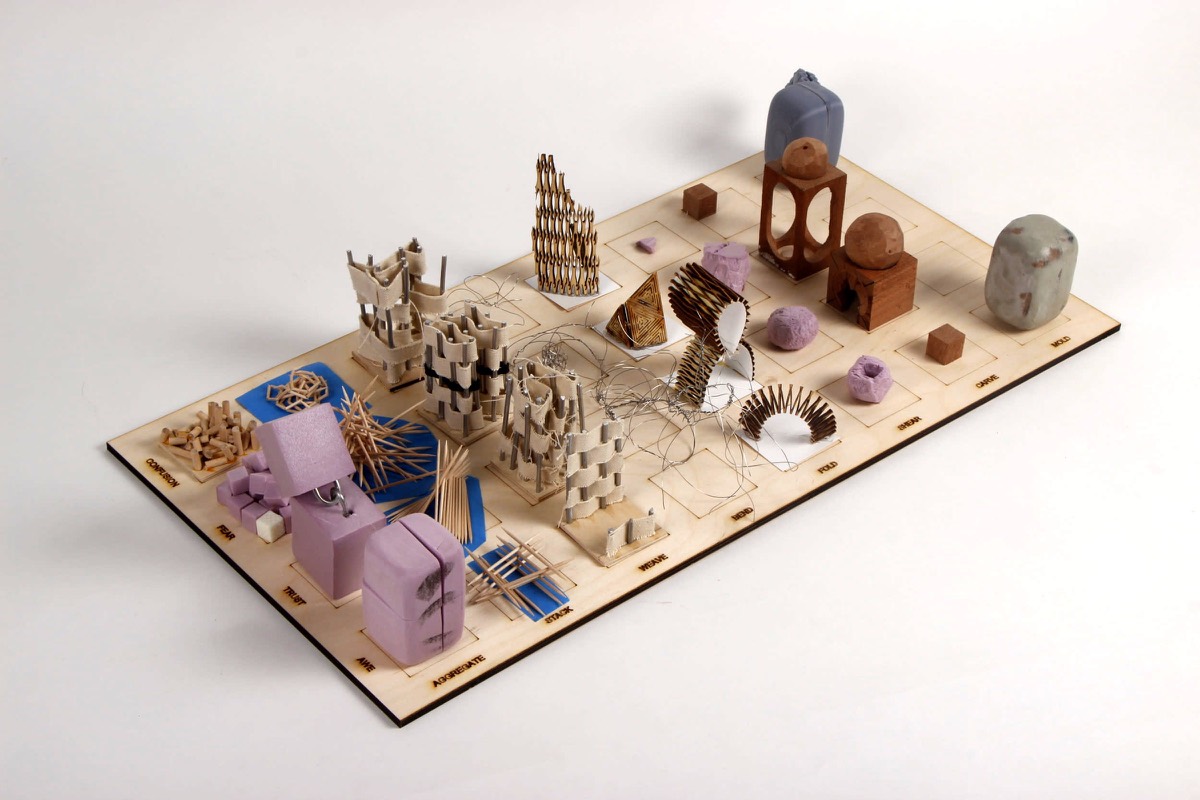 A plywood board crowded with small objects in wood, wax, lilac foam, and brass, each in its cell