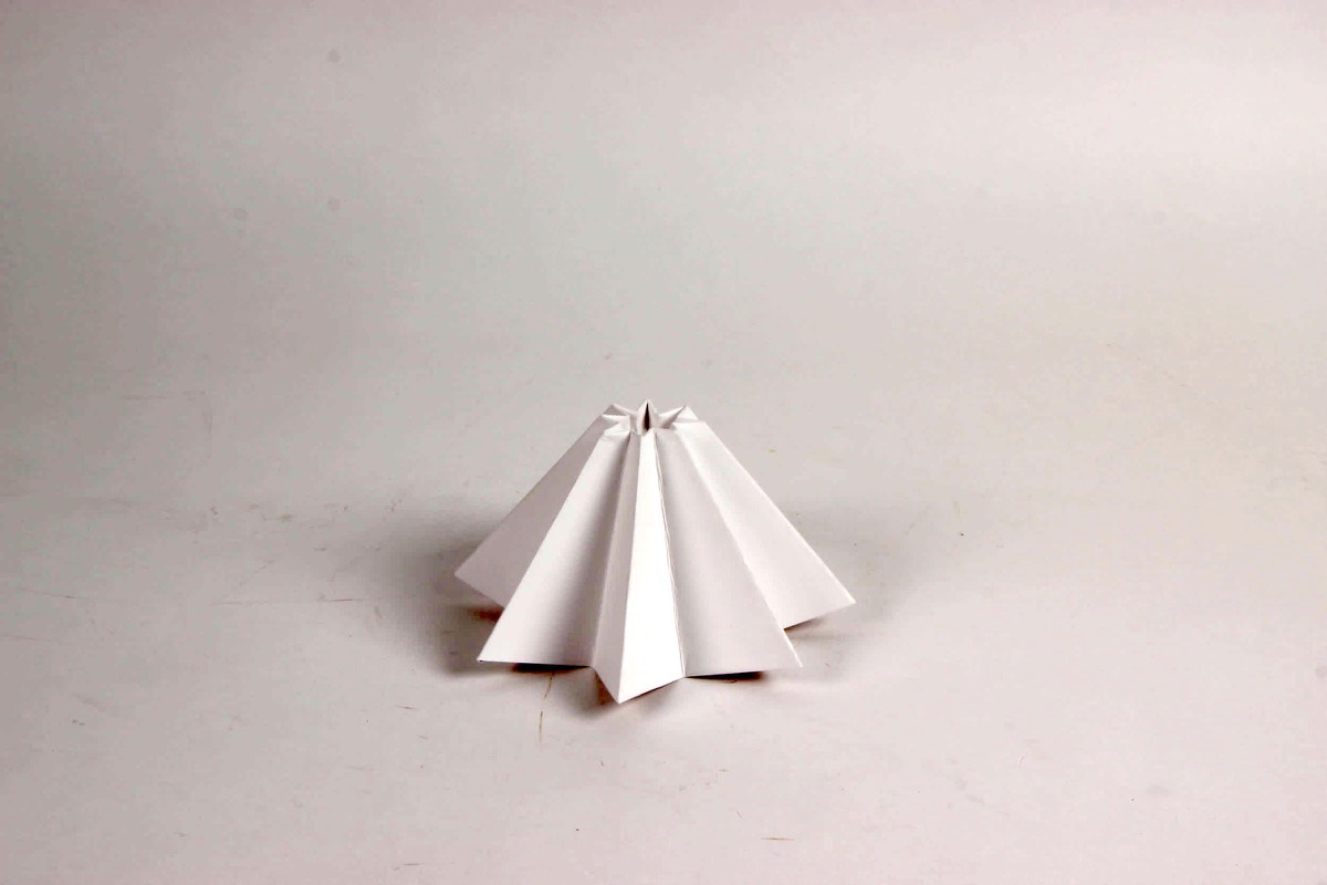 A white paper form folded into a star-like tent on a grey ground