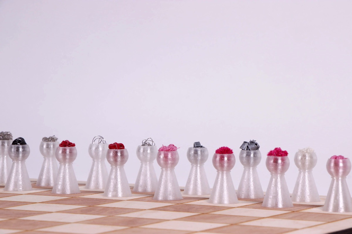 A row of turned aluminium pawns topped with small red and clear spheres