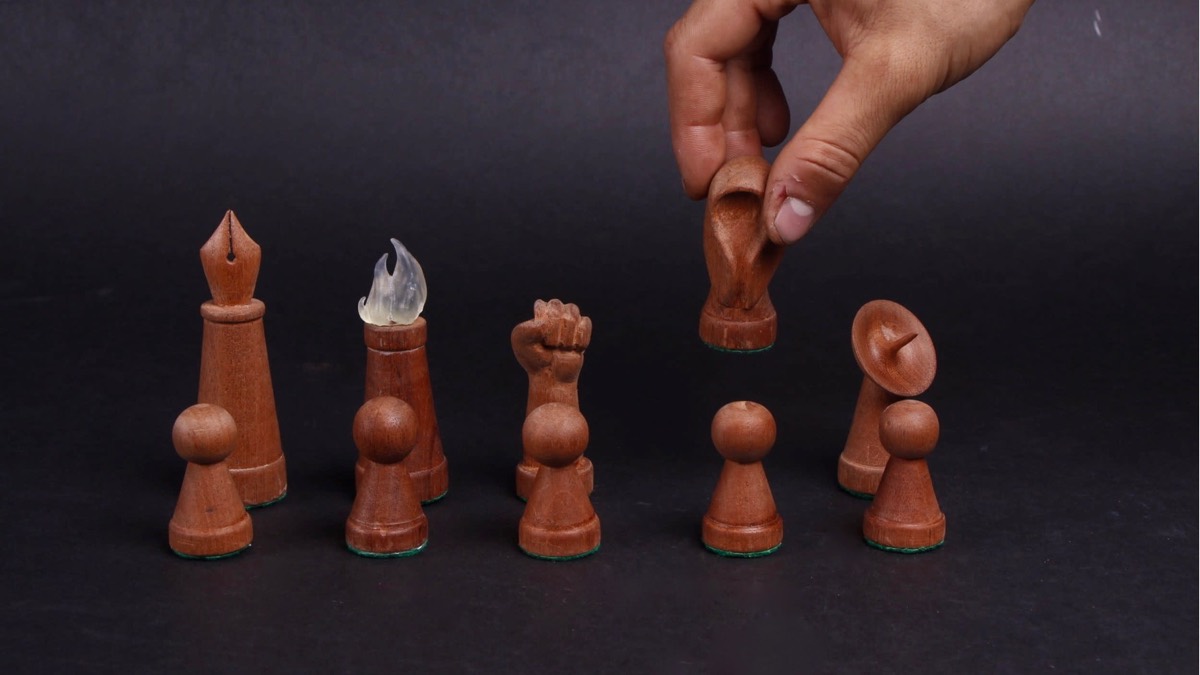 A hand lifting a carved terracotta horse-head piece from a set of six