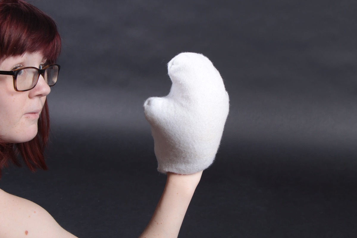 A student in profile with a white felted mitt on one hand