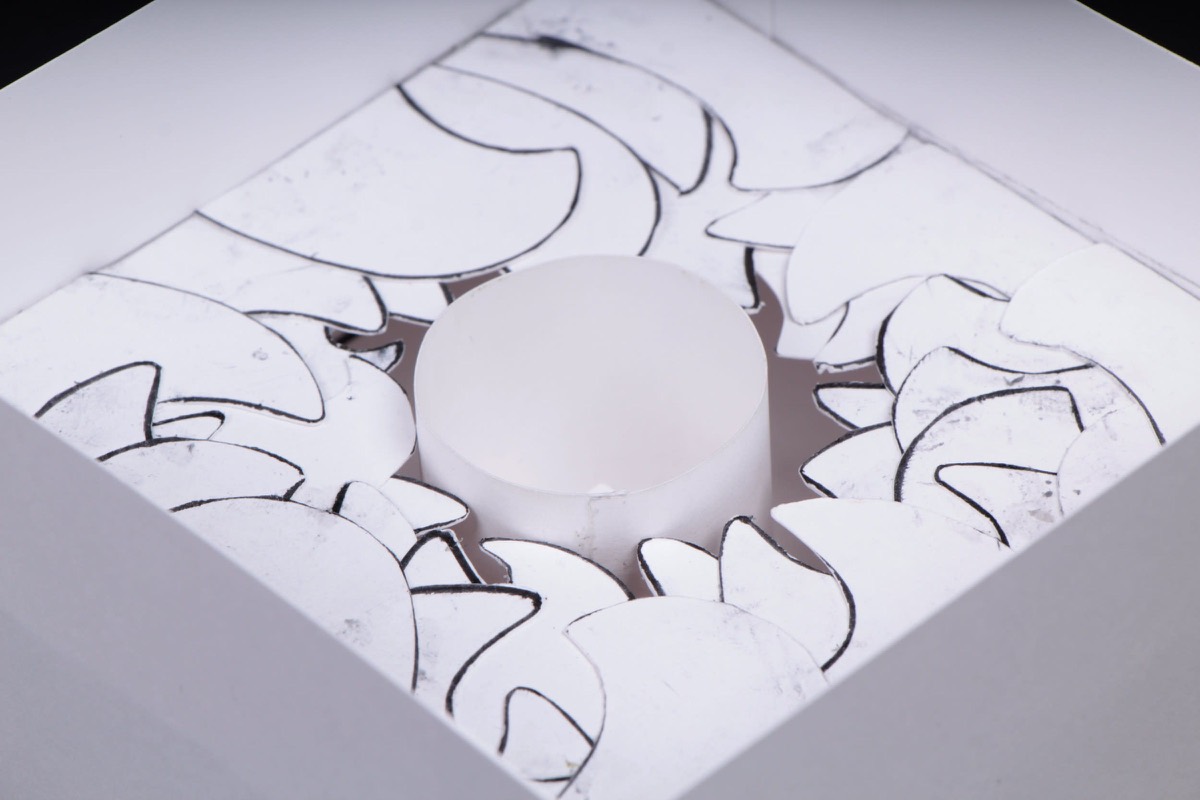 A white paper square with a cut circular opening and curling flaps