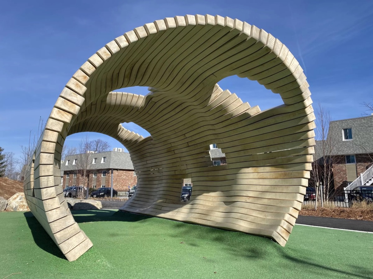 The eroded end of the plank arch on green surfacing against blue sky, brick blocks behind