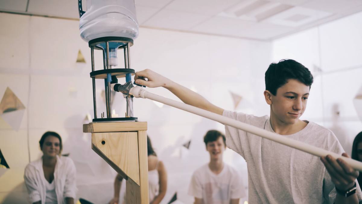 A student pouring from a suspended vessel into the tower's basin