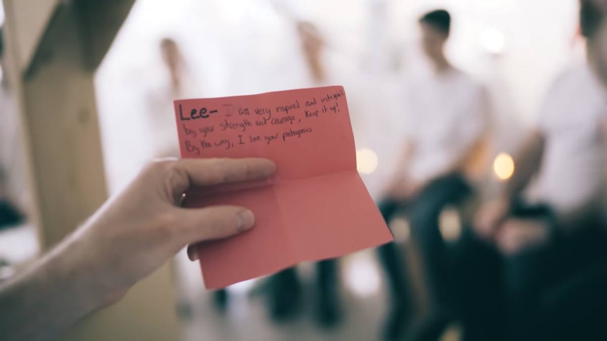 A hand holding a red card with a handwritten note