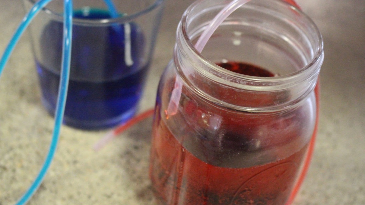 Two jars of blue and red dyed water joined by tubing